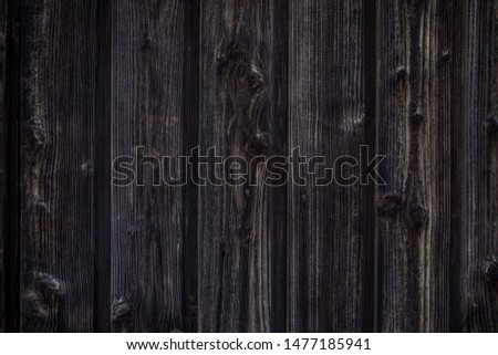 Dark brown wooden background. Natural wooden boards are saturated with dark oil. Vertical boards with knots. Tinted.
