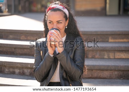 pretty happy cheerful young woman with paper coffee cup on the street