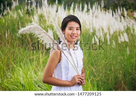 Vintage style portrait photography of pretty Asian girl in white Indian grass flower or Saccharum spontaneum park, selected focus.