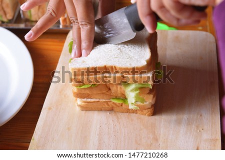 The picture is using a knife to divide the data. Large sandwiches stacked with ham salad.