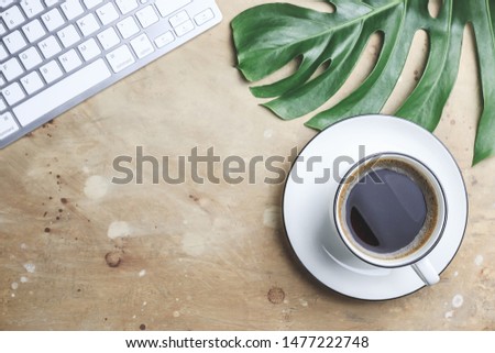 Office desk with hot coffee, plant, keyboard on beige stone background. Business desk minimal style concept, female freelance. Copy space. Top view. Flat lay