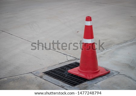 Traffic cone on the asphalt surface with partly rubbed out white road background