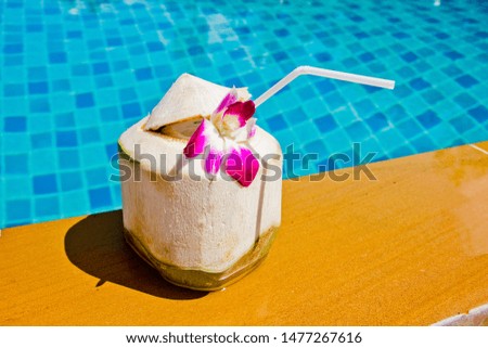 Coconut water is ready to serve. Decorated with purple flowers and located beside the pool side