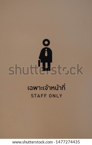 Only Staff sign on the wall with Thailand langauge capture by camera