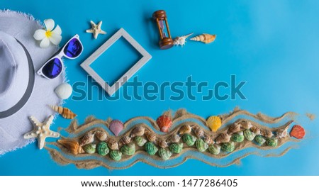 Beach  accessories   including  straw  hat,sunglasses,blank  wooden  picture  frame,hourglass  and  colorful  seashells  on  blue  background  for  summer  concept