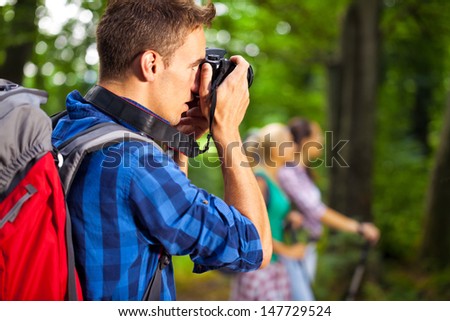 Hiking photographer taking pictures, young man hiker enjoying nature landscape