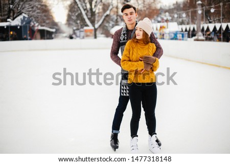 Beautiful couple have fun in a ice arena. Elegant girl in a yellow sweater.