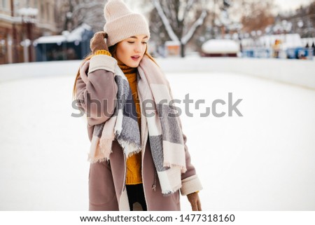 Girl in a winter park. Beautiful lady in a yellow sweater. Woman in a ice arena