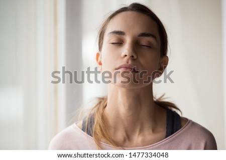 Close up calm mixed race millennial woman in casual clothes sitting with closed eyes, relaxing, meditating, doing breathing exercises, thinking, reminding good memories, visualizing future. Royalty-Free Stock Photo #1477334048