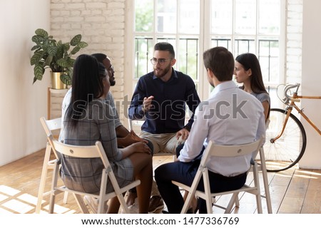 Male psychologist counselor therapist coach speak at group therapy session psychotherapy meeting supporting helping patients in substance addiction mental problem talk sit in circle in rehab concept Royalty-Free Stock Photo #1477336769