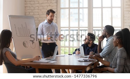 Serious male manager presenter businessman speaker give business presentation to diverse employees group at office meeting workshop in conference room teach team at corporate training lecture seminar