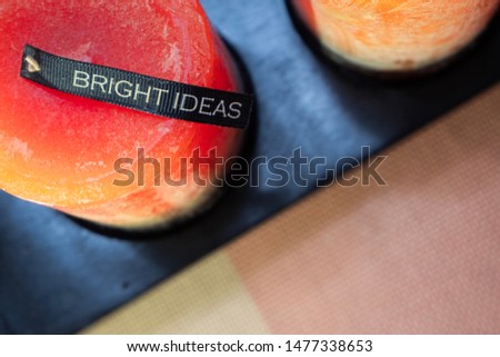 Bright Ideas text on top of red orange candle background. Innovation concept. Provided with space at the center for text, graphics and other content  - shallow depth of field
