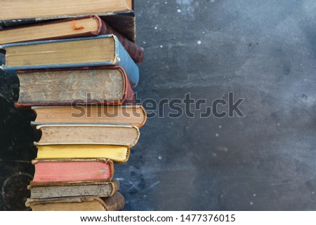 Pile of multicolored books, education, reading, back to school concept, copy space on blackboard