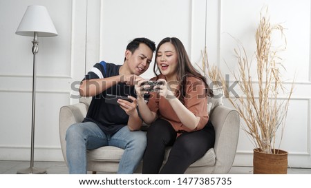 Image of excited young man and woman playing together and competing in video games on smartphones isolated over yellow background