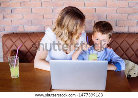 Young mom and her son looking at laptop at the table. She is showing him something. Parenthood and technology concept