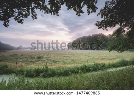 beautiful sunrise over dutch field with trees and a colorful sky