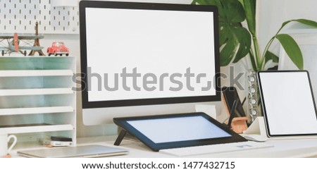 Modern comfortable home office with blank screen desktop computer and tablet with office supplies 