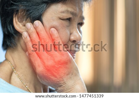 TMD and TMJ concept: Temporomandibular Joint and Muscle Disorder. Old Asia woman hand on cheek face as suffering from facial pain, mumps or toothache  Royalty-Free Stock Photo #1477451339