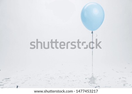 Blue balloon surrounded by silver confetti on white background. Birthday and holidays background.