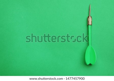 Plastic dart arrow on green background, top view with space for text