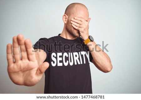Young safeguard man wearing security uniform over isolated background covering eyes with hands and doing stop gesture with sad and fear expression. Embarrassed and negative concept.