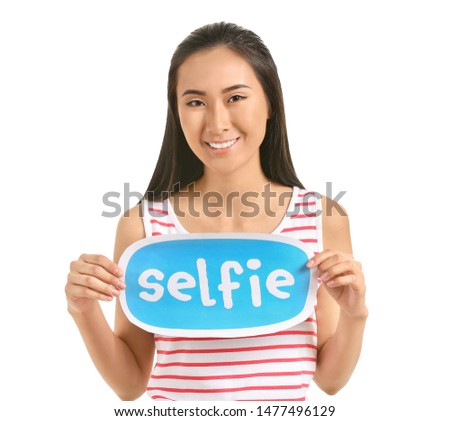 Female Asian blogger holding paper with text SELFIE on white background