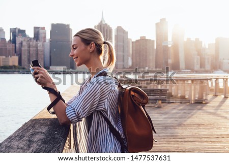 Positive Caucasian hipster tourist checking photos at retro camera enjoying summer trip for exploring America culture and discover New York districts, concept of amateur photography and hobby