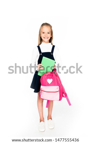 full length view of cute schoolgirl holding backpack and book on white background