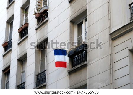 Old white facade with red white blue french flag. Paris, France.