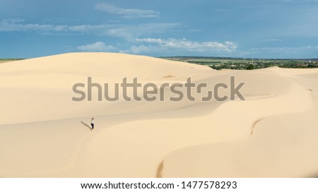 Small female silhouette walking in desert sand dunes of Mui Ne, Vietnam