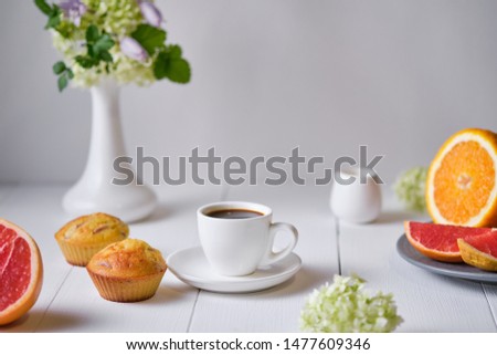 Coffee and fruit muffins with fresh peach for breakfast. Morning table with dessert, espresso, fruits and flowers in a vase on a white wooden table.