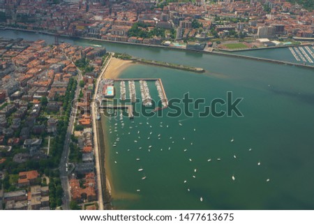 Aerial view from aircraft window of Bilbao surrounding area. Photography of houses roofs, river, Bay of Biscay, beach in Basque country in summer day. Suitable for greeting card, postcard, poster
