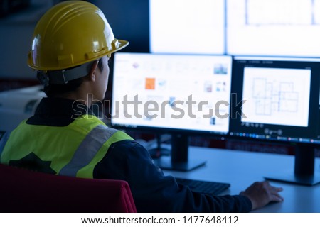 Industrial Engineering works in front of monitoring screen in the production control center. technology concept. Royalty-Free Stock Photo #1477648412