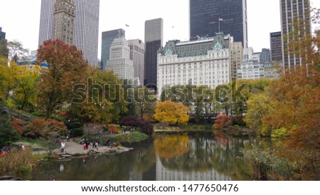 New York Central park lake with reflection of famous hotel, skyscrapers and beautifully colored trees.