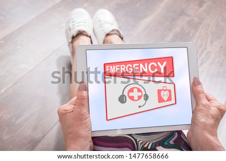 Woman sitting on the floor with a tablet showing emergency concept