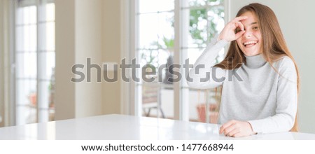 Wide angle picture of beautiful young girl kid wearing casual sweater doing ok gesture with hand smiling, eye looking through fingers with happy face.