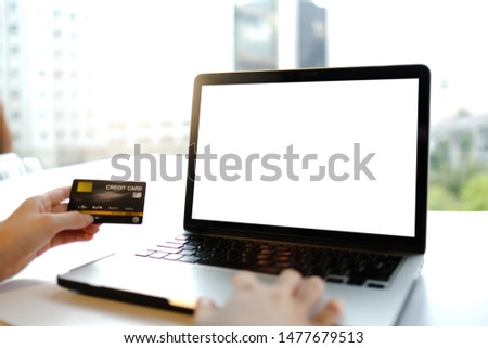Close up of woman using blank laptop and credit card sending massages and shopping online on the coffee shop.