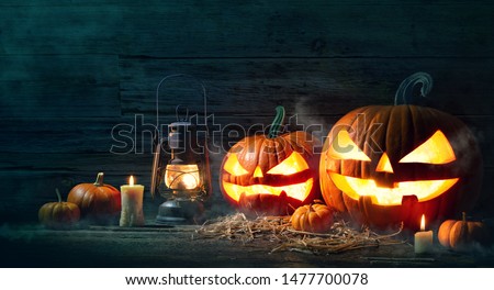 Halloween pumpkin head jack lantern with burning candles in scary deep night