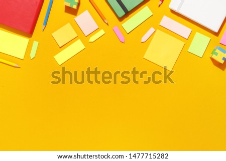 Composition of several stationery notebooks of different colors on a yellow background. Top view