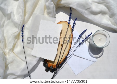 Wedding, birthday stationery layout desktop mock up on white gauze background. Envelope, greeting card, invitation with candle. Lavender and wood slice. Flat lay, top view scene
