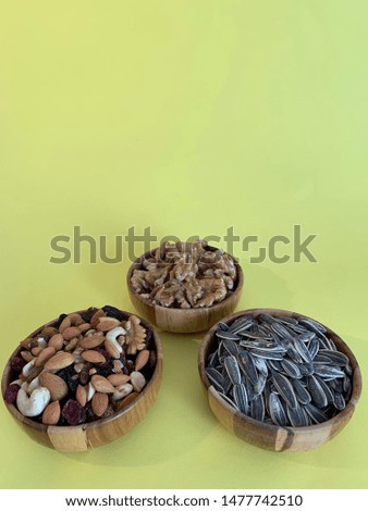 Black sunflower, walnut and some mixed cookies in the wooden pots. Grey background. Angled shot.