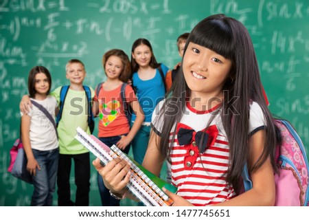 Little schoolgirl and group child on classroom background Royalty-Free Stock Photo #1477745651