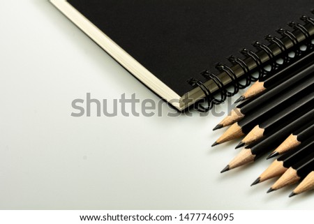 black diary book and a pencil on grey desk background with copy space. - top view.