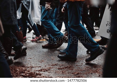 Peoples legs in a crowd as they walk down the street