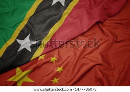 waving colorful flag of china and national flag of saint kitts and nevis. macro