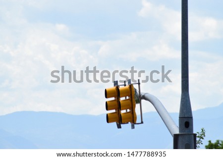 Traffic light street lamp posts and mountains by clouds.