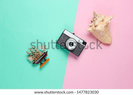 Minimalistic travel still life. Seashells, retro camera, decorative ship blue pink pastel background. Top view