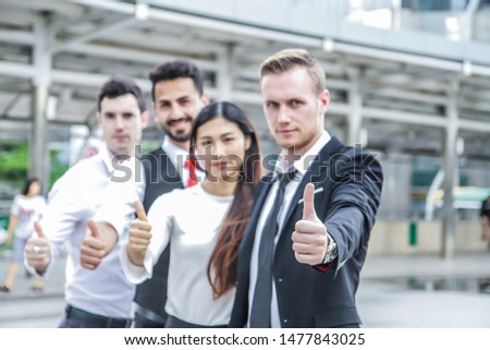 International Business Group thumb up. Successful positive interracial group of businessmen and businesswomen team, giving thumbs up