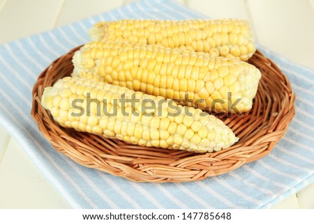 Fresh corn on wicker mat, on wooden background