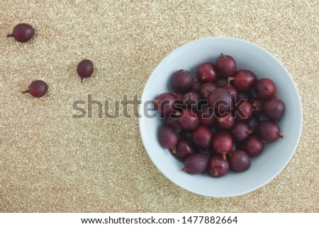 Red gooseberries in a bowl on a glittering golden background. Photo was taken from directly above. 